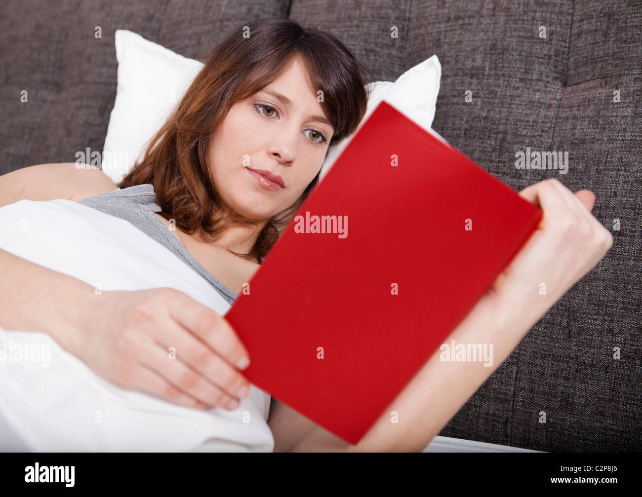 Bella giovane donna sdraiata sul letto e la lettura di un libro Foto Stock