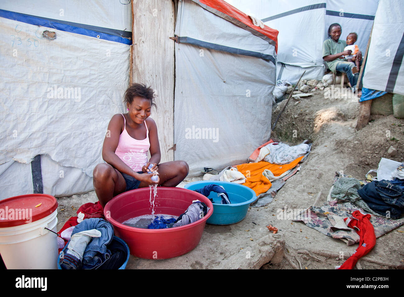 Donna lavando i suoi vestiti in Petionville tenda camp , Haiti Foto Stock