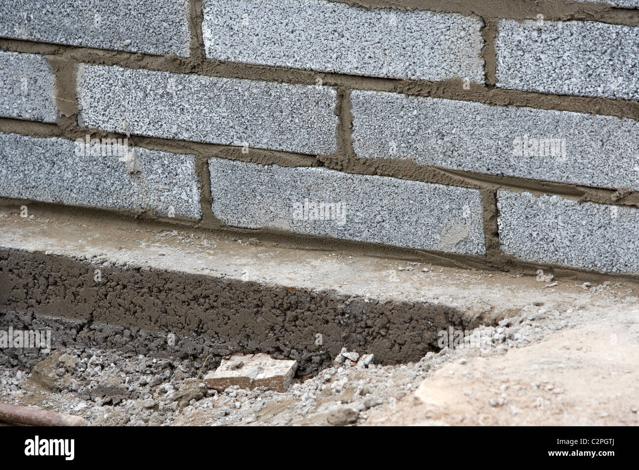 Parete di muratura con mezza brezza di cemento blocca la costruzione di un blocco di parete di ritegno su fondazioni in calcestruzzo nel Regno Unito Foto Stock