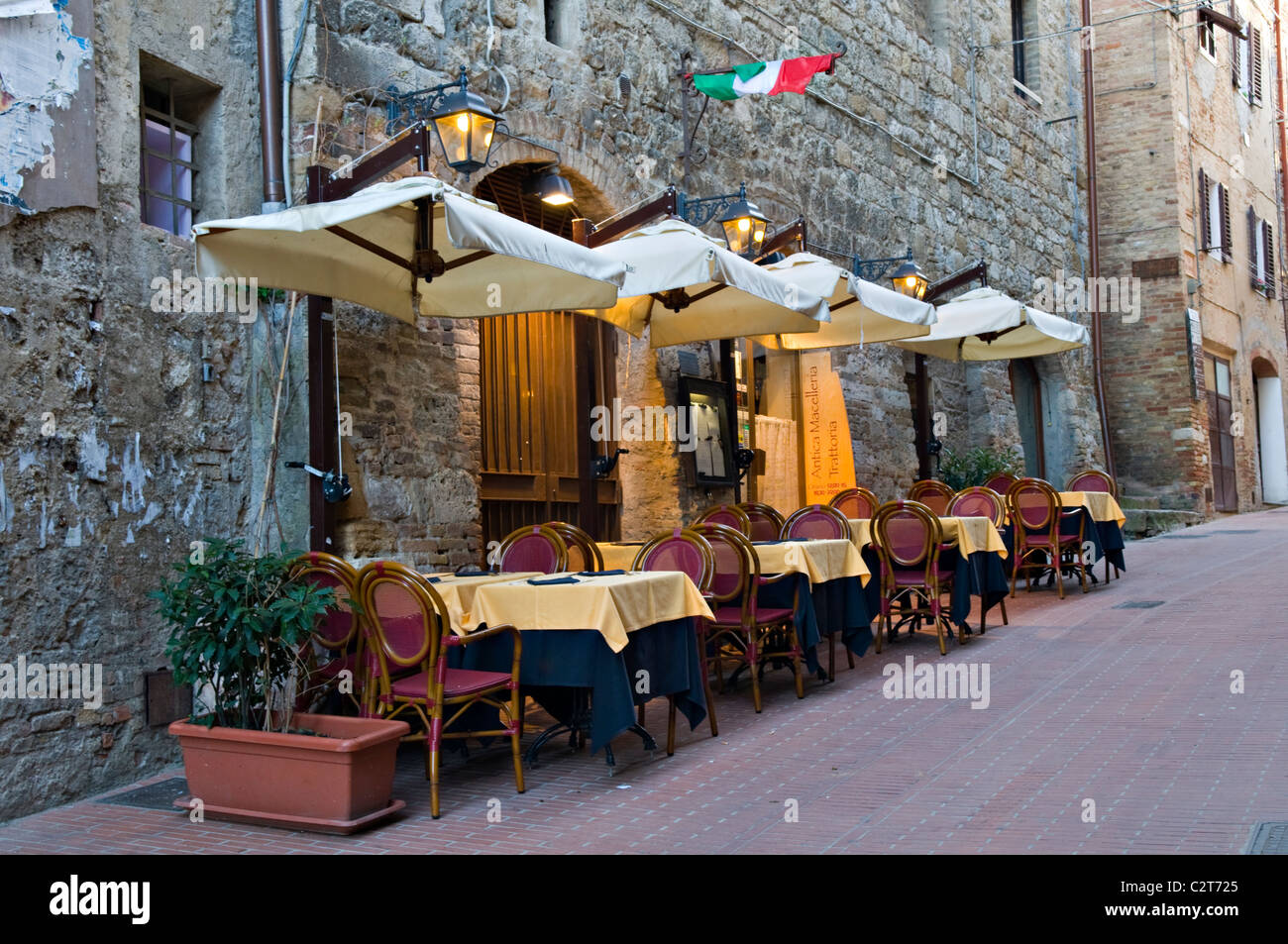 I tavoli fuori un ristorante in una tranquilla strada laterale a San Gimignano, Italia Foto Stock