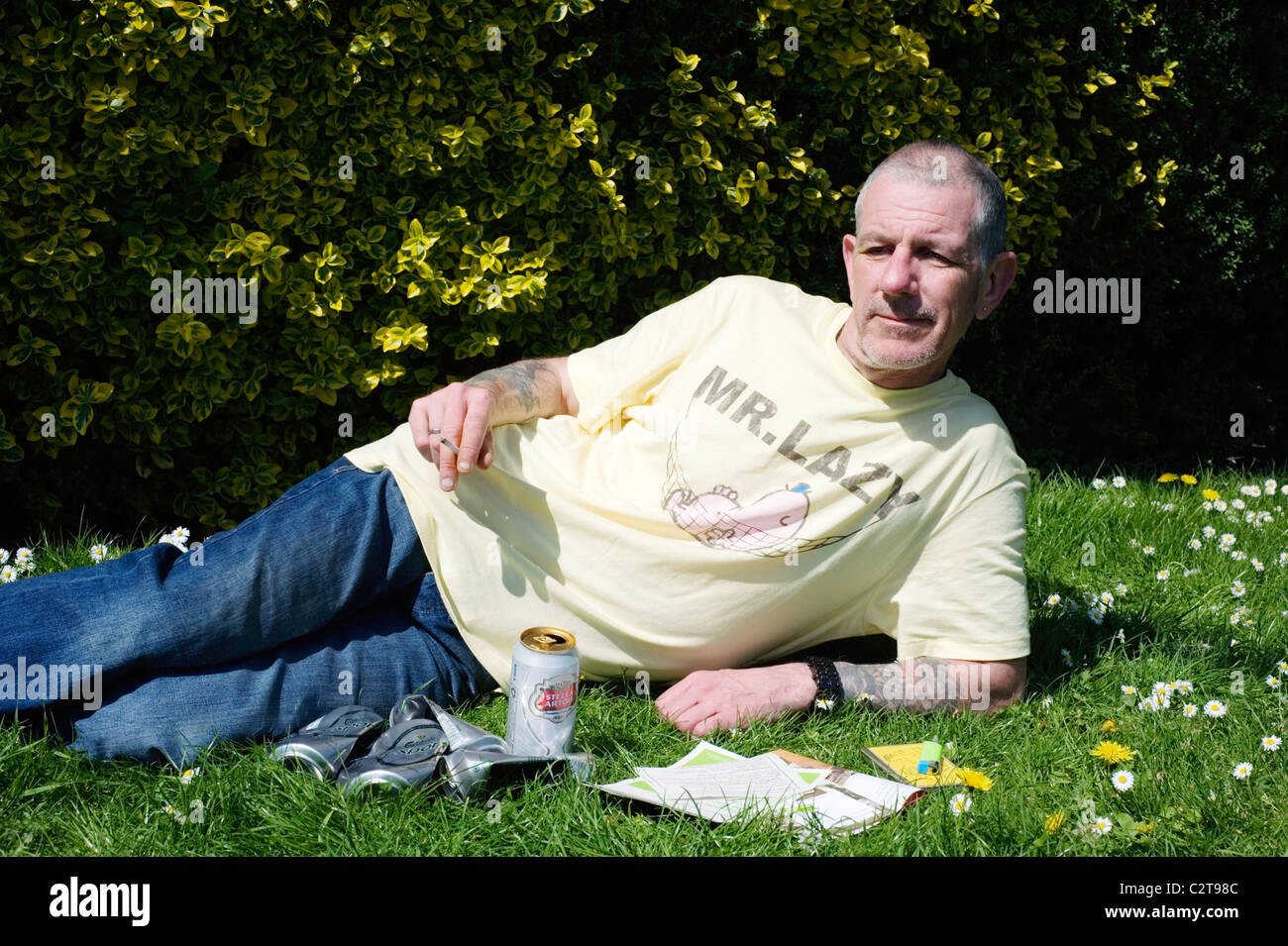 Disoccupati uomo nel parco pubblico godendo il sole con benefici volantini birra e sigarette Foto Stock