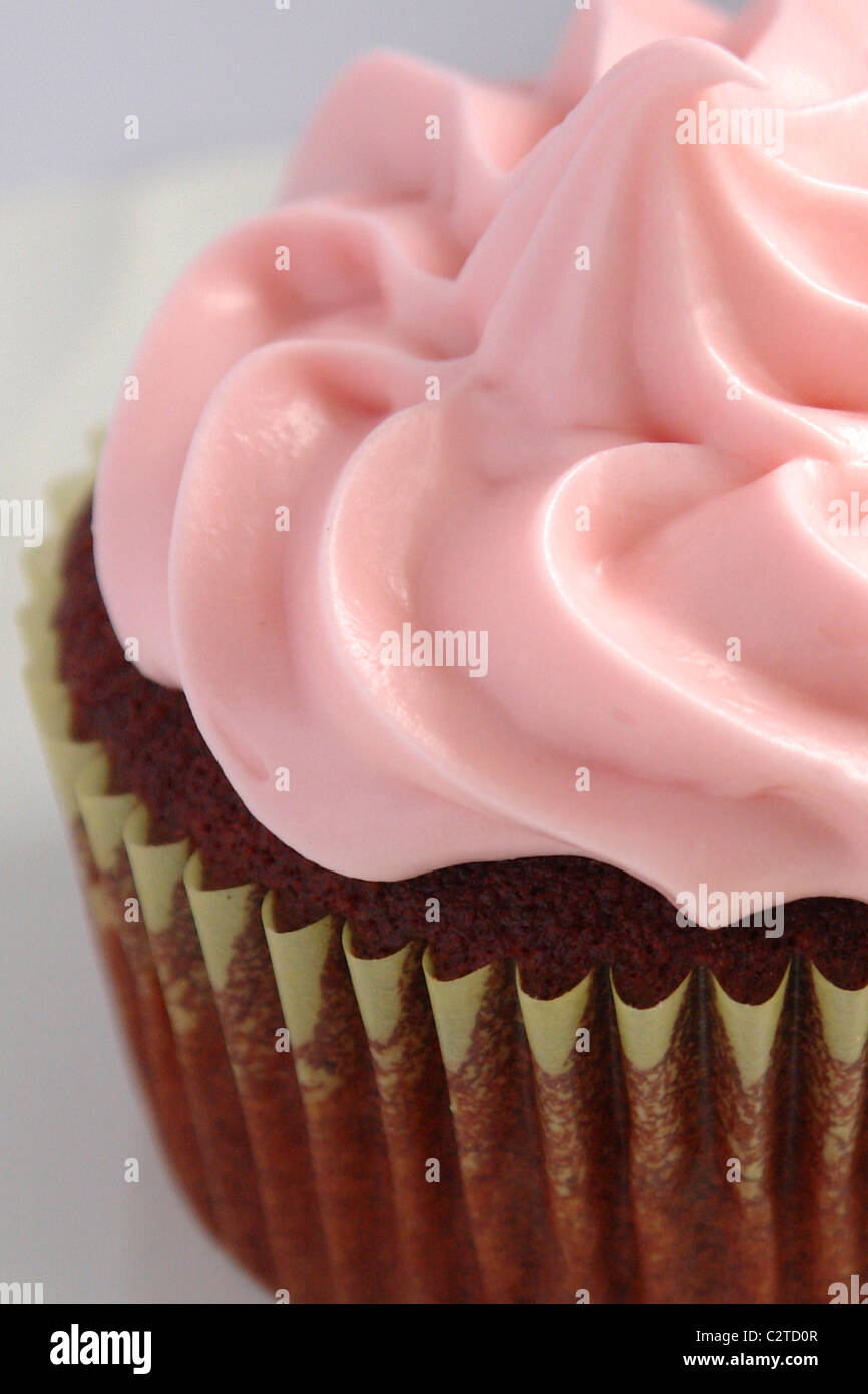 Closeup ancora in vita di velluto rosso Cupcake rosa con la glassa di formaggio cremoso Foto Stock