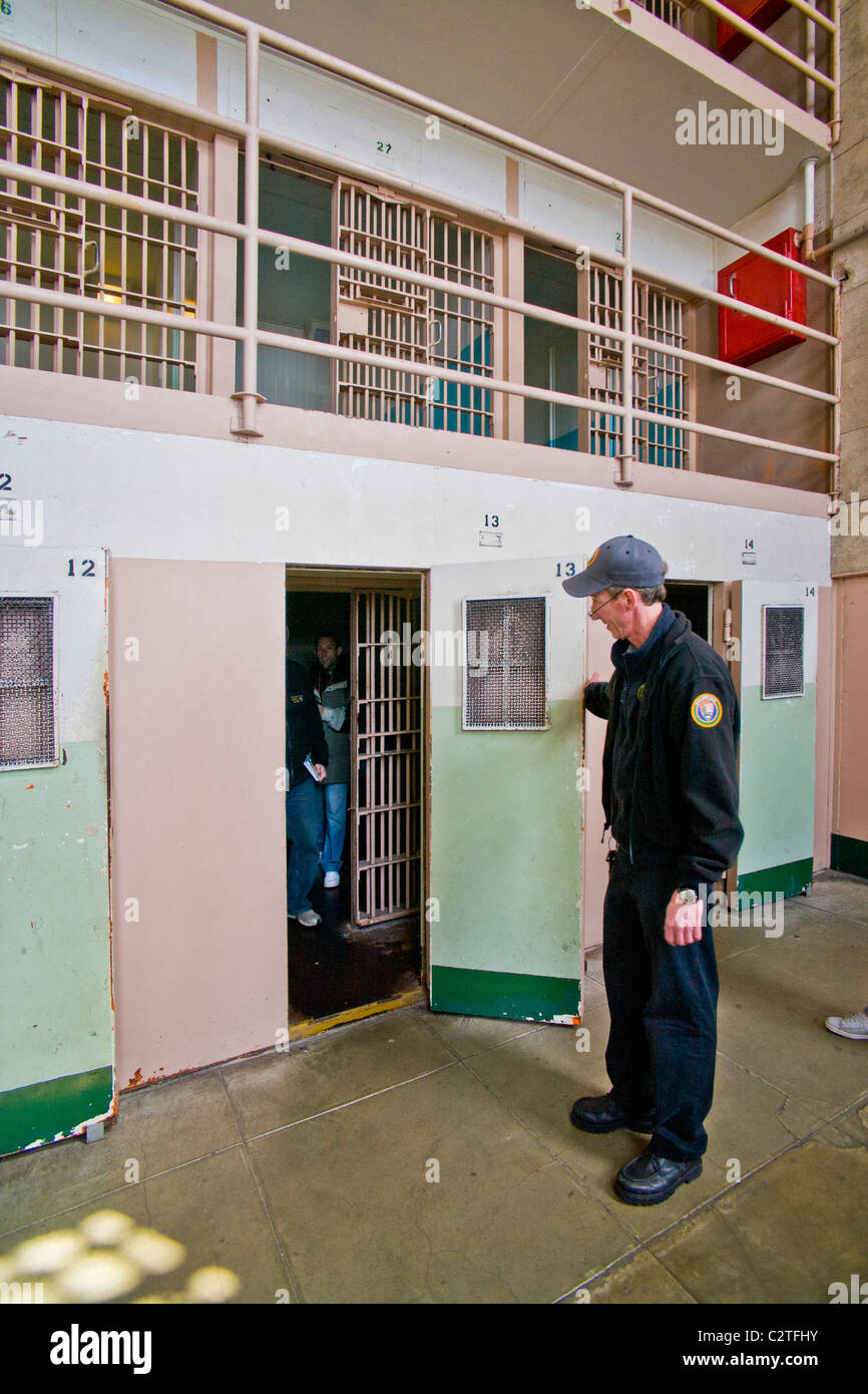 Un volontario in uniforme apre la porta di un confino solitario cella per turisti in Cellblock D all'ex prigione di Alcatraz. Foto Stock