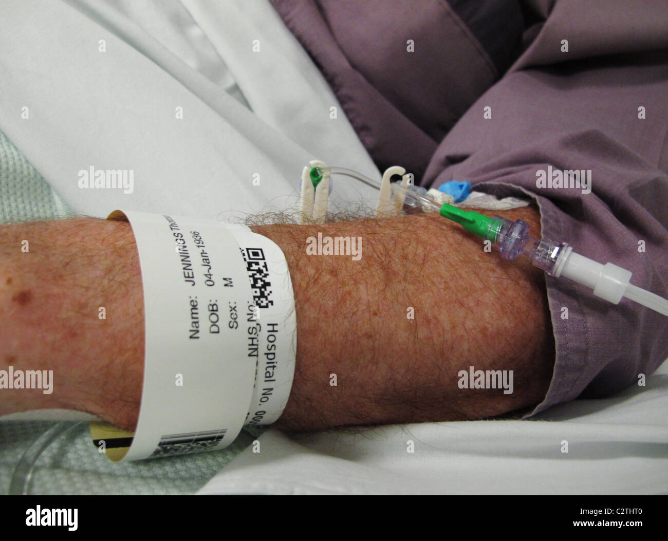 Anziani mans braccio in ospedale con il nome di tag e gocciolatoio Foto Stock