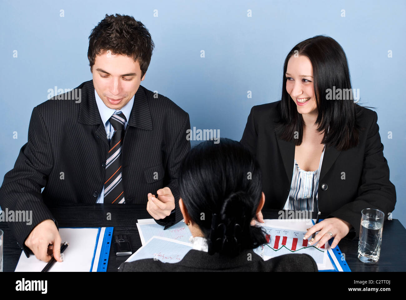 La gente di affari avente un colloquio di lavoro con una donna che rimane con la schiena e si diverte e ridere Foto Stock