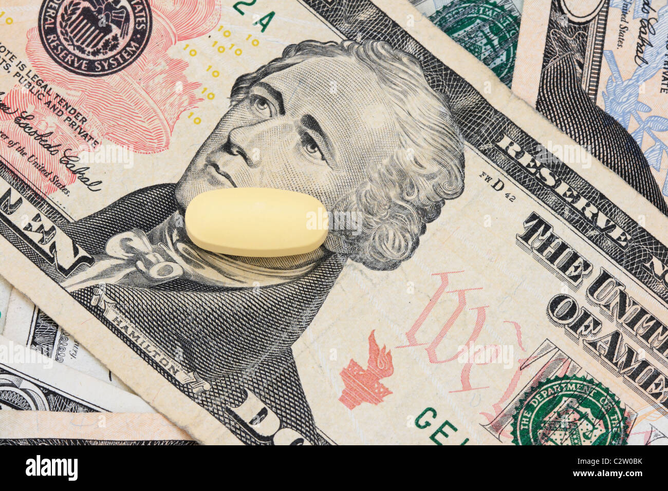 Macro di una singola pastiglia gialla su un certo numero di noi fatture su supporto cartaceo con i cinque dollari sulla parte superiore Foto Stock