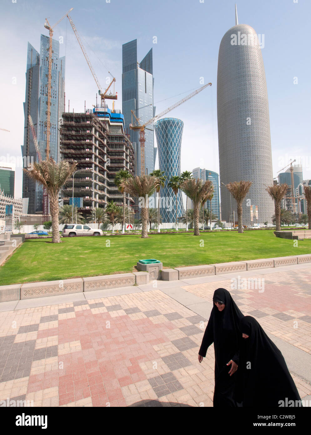 Le donne a piedi sulla Corniche con moderne torri di uffici e sullo skyline nel quartiere degli affari a Doha in Qatar Foto Stock