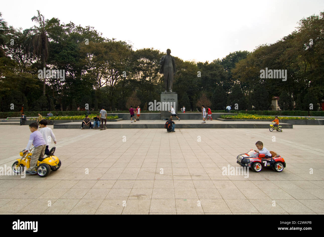 Orizzontale di ampio angolo dei bambini la guida intorno a Lenin statua in azionato a batteria auto nel Parco Lenin, centro di Hanoi Foto Stock