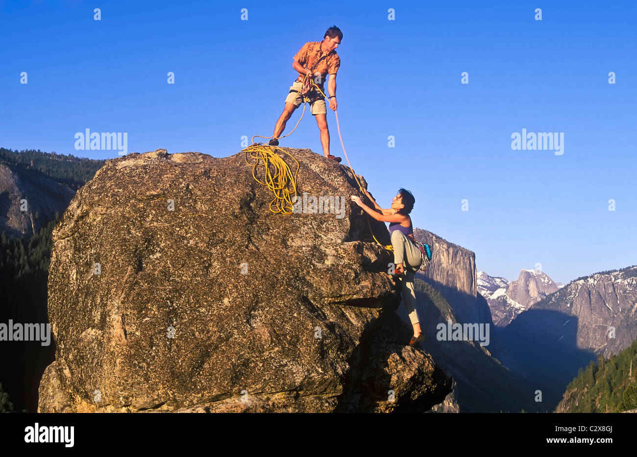 Team di arrampicatori lotta per raggiungere il vertice di un ripido pinnacle. Foto Stock