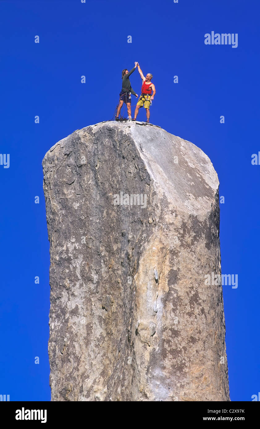 Team di arrampicatori celebrare dopo una lotta per raggiungere la cima di un impegnativo pinnacle. Foto Stock