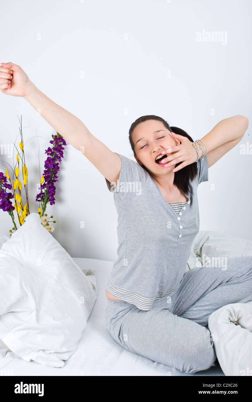 Giovane donna stretching e sbadigli al mattino o prima di dormire sul suo  letto Foto stock - Alamy