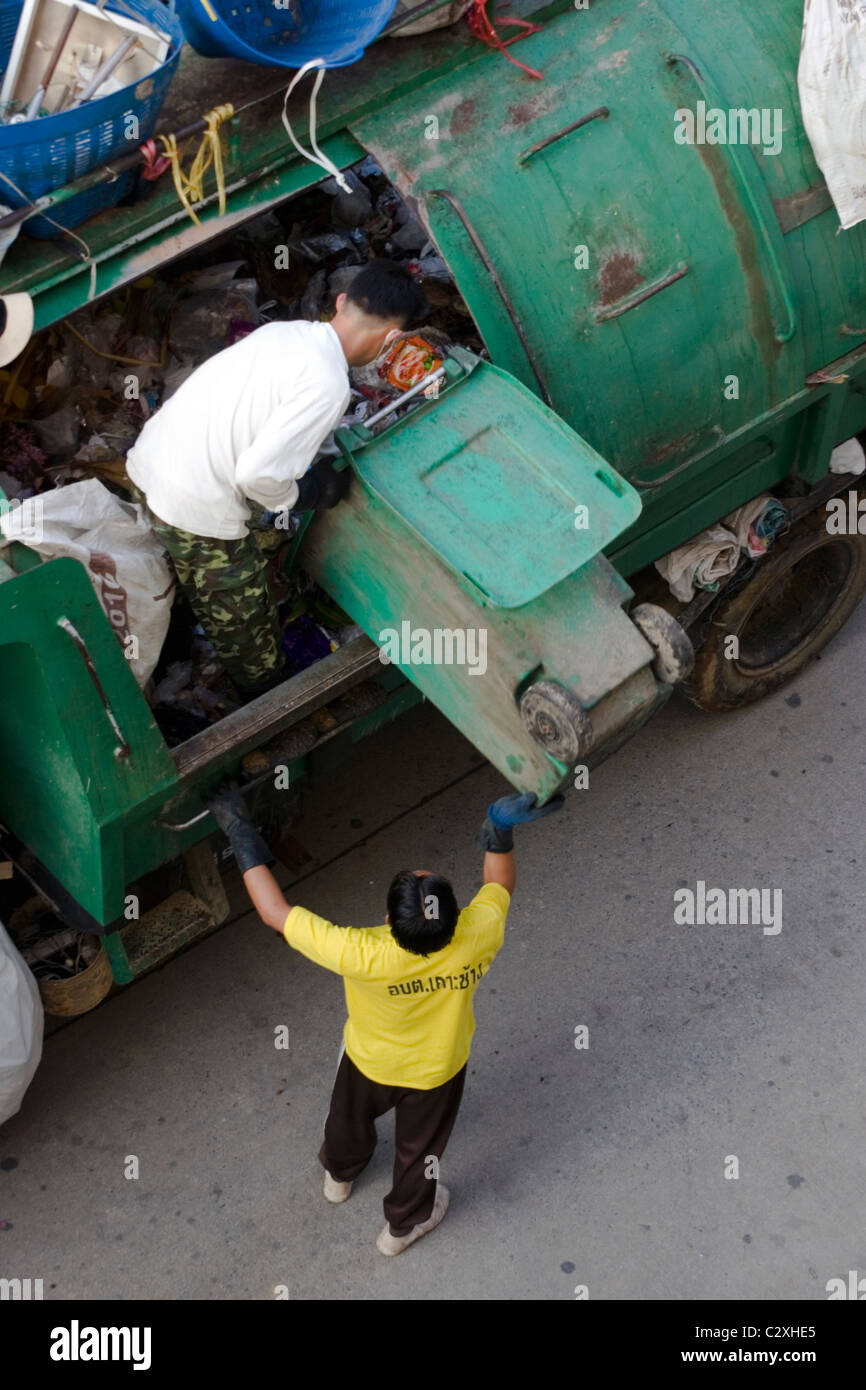 Due uomini sono in fase di carico di un camion della spazzatura con cestino su una strada di città in Mae Sai, (SAE) Thailandia. Foto Stock