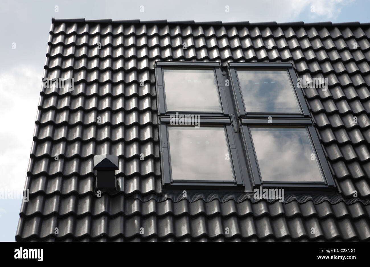 Nero brillante tetto di tegole con quattro lucernari in un rettangolo Foto Stock