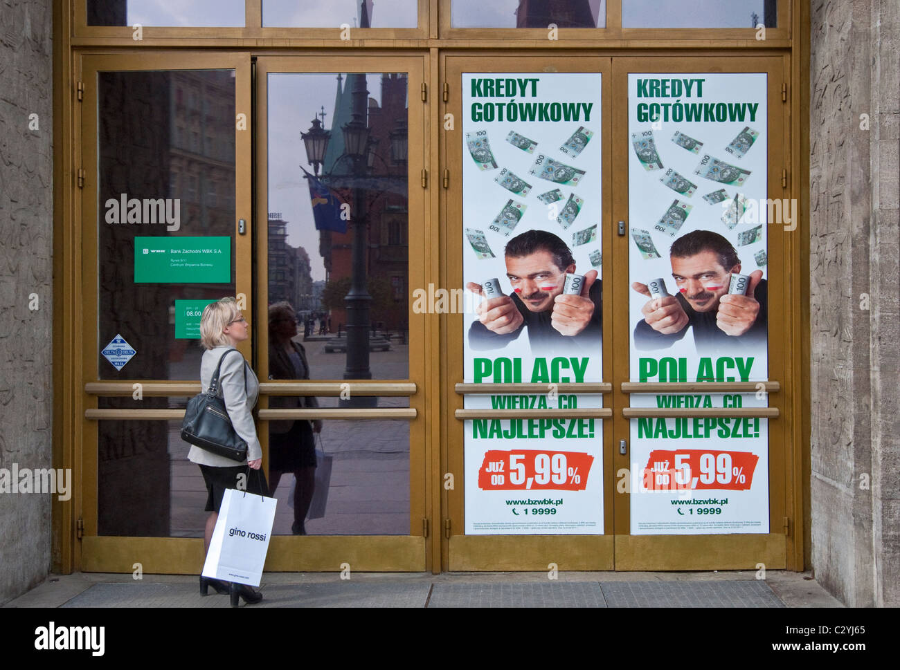 Il cliente entrando in banca, poster pubblicitari con l'attore Antonio Banderas circondato da zloty banconote a Wrocław, Polonia Foto Stock