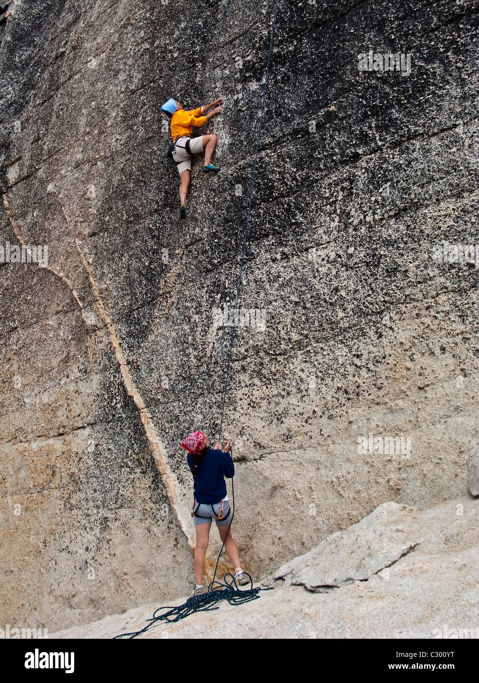 Team di arrampicatori scalare una ripida roccia nelle montagne della Sierra Nevada, in California. Foto Stock