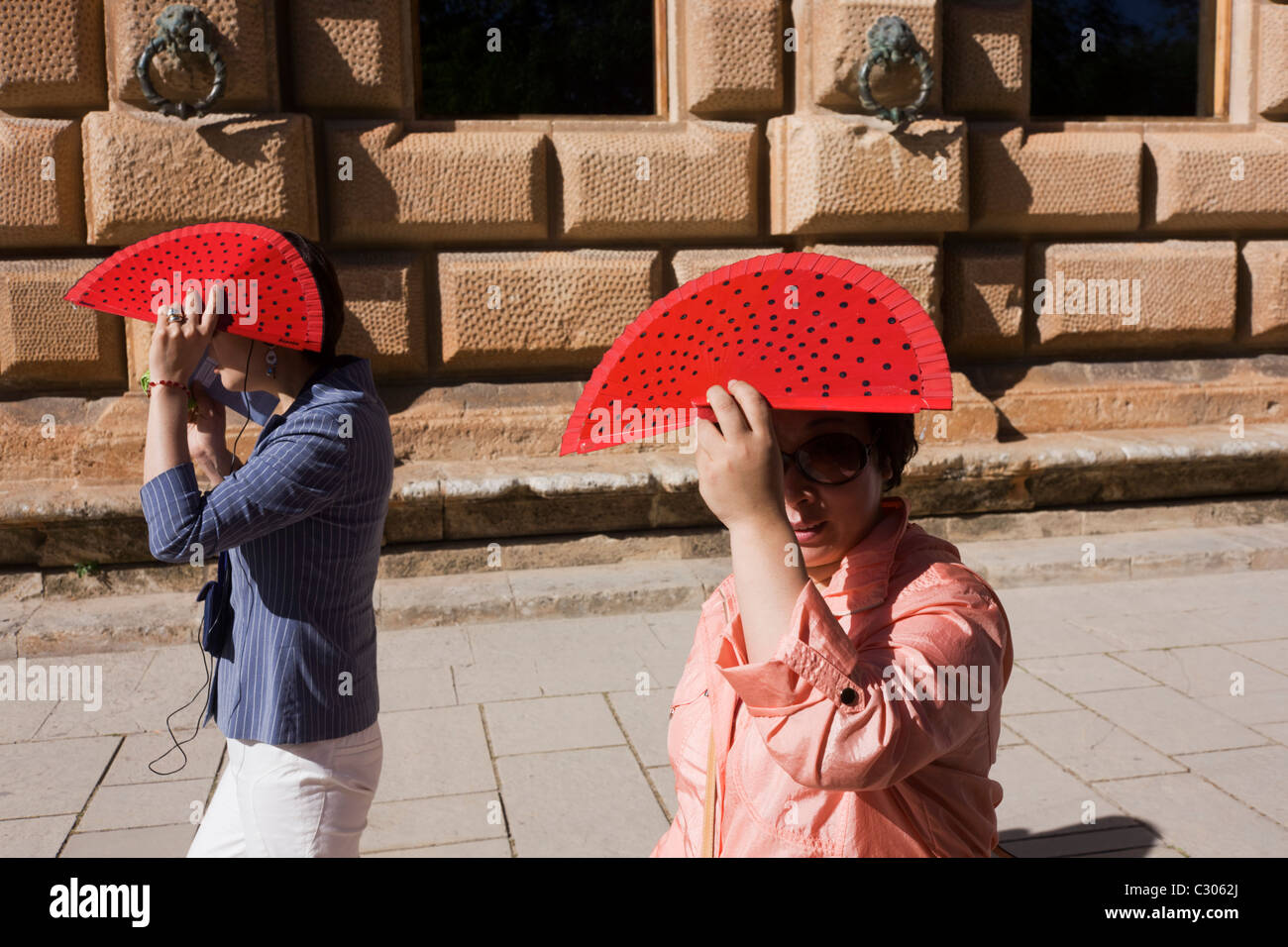 Due donne turisti provenienti da Asia a piedi sotto il sole a Alhambra, entrambe le telecamere di contenimento. Foto Stock