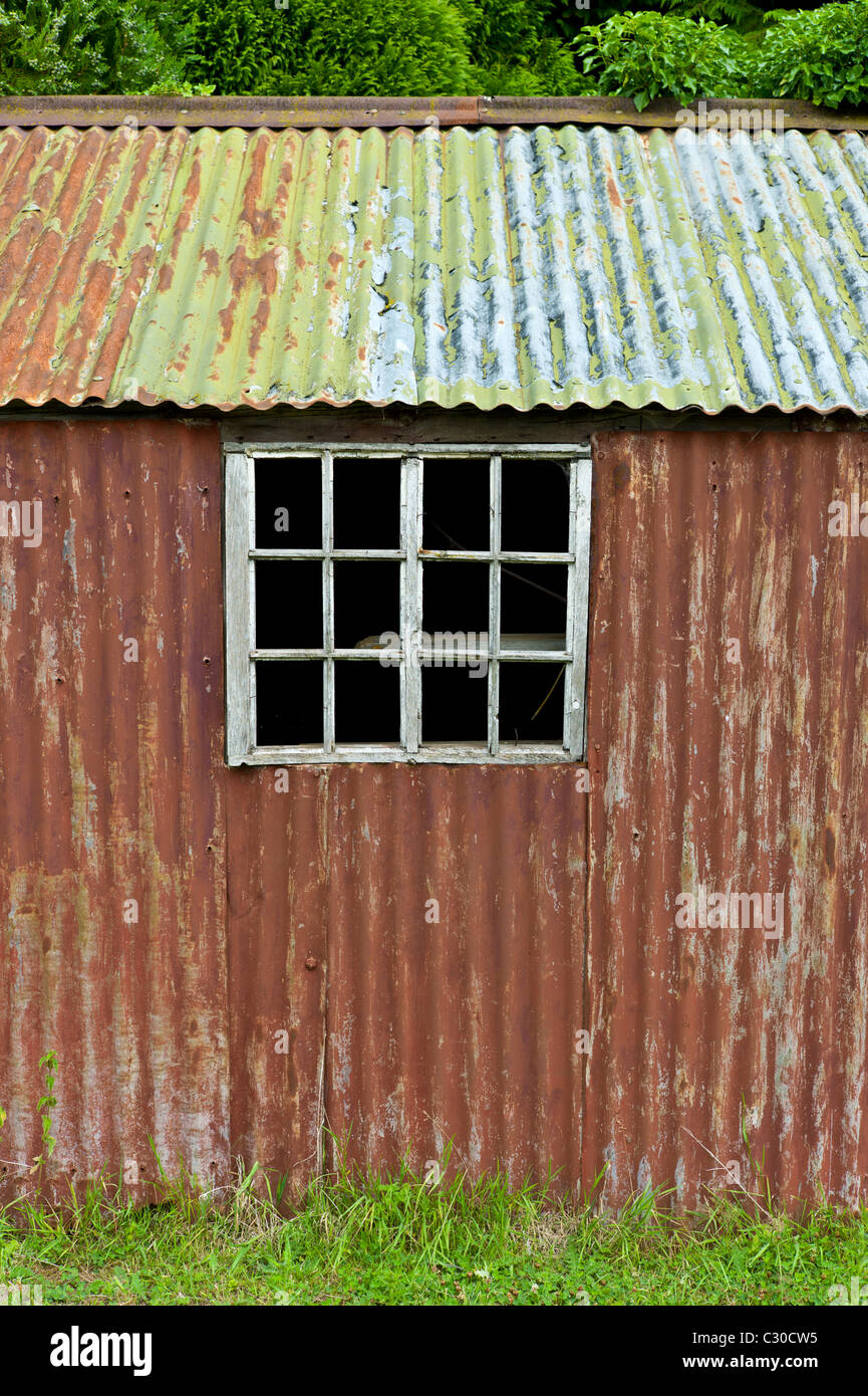 Rusty ferro corrugato sparso in Cotswolds village di Bledington, Oxfordshire, Regno Unito Foto Stock