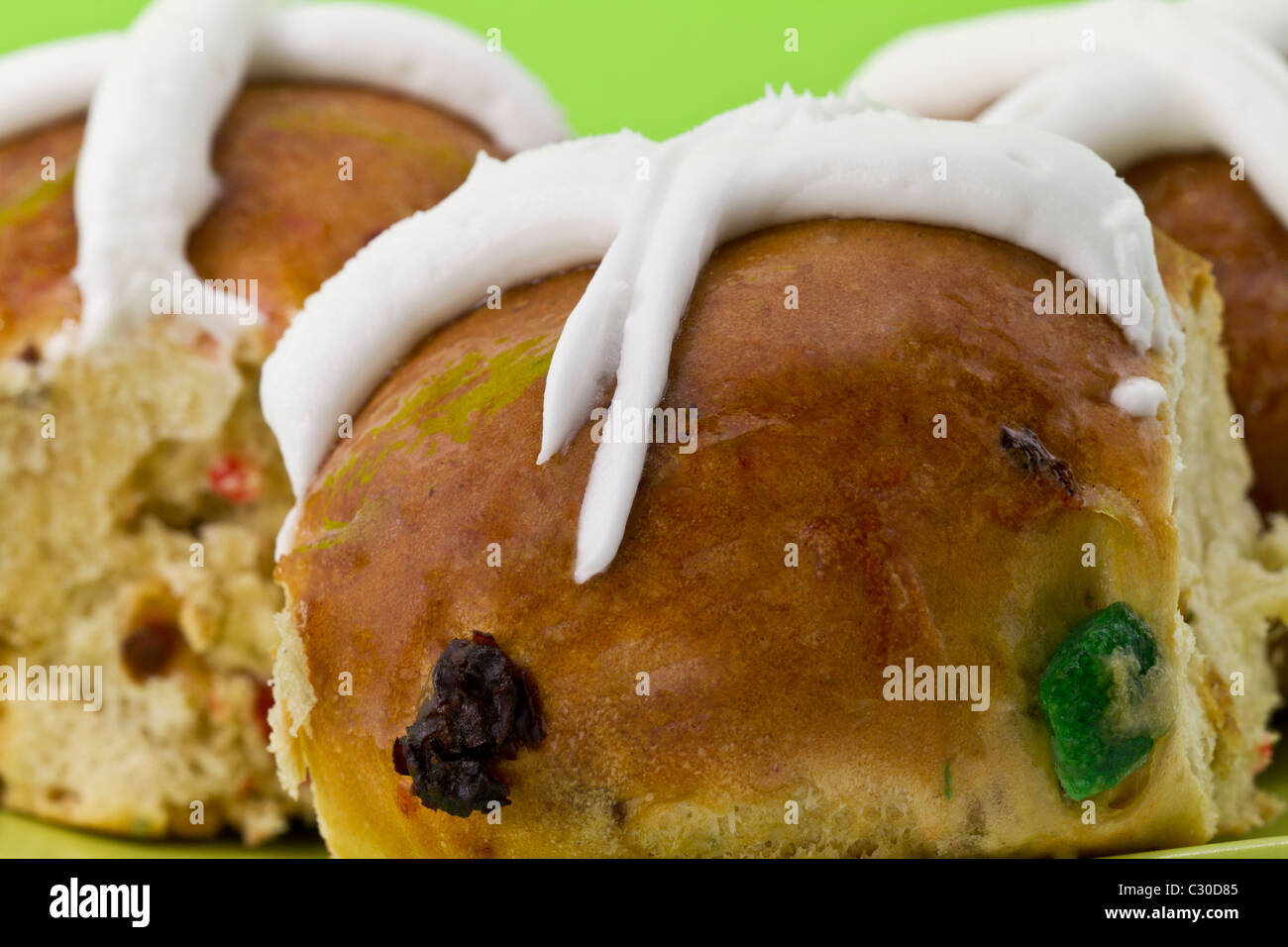 Chiudere l immagine di calde tradizionali ciambelle a croce con una croce bianca glassa e tagliate a dadini la frutta secca. Foto Stock