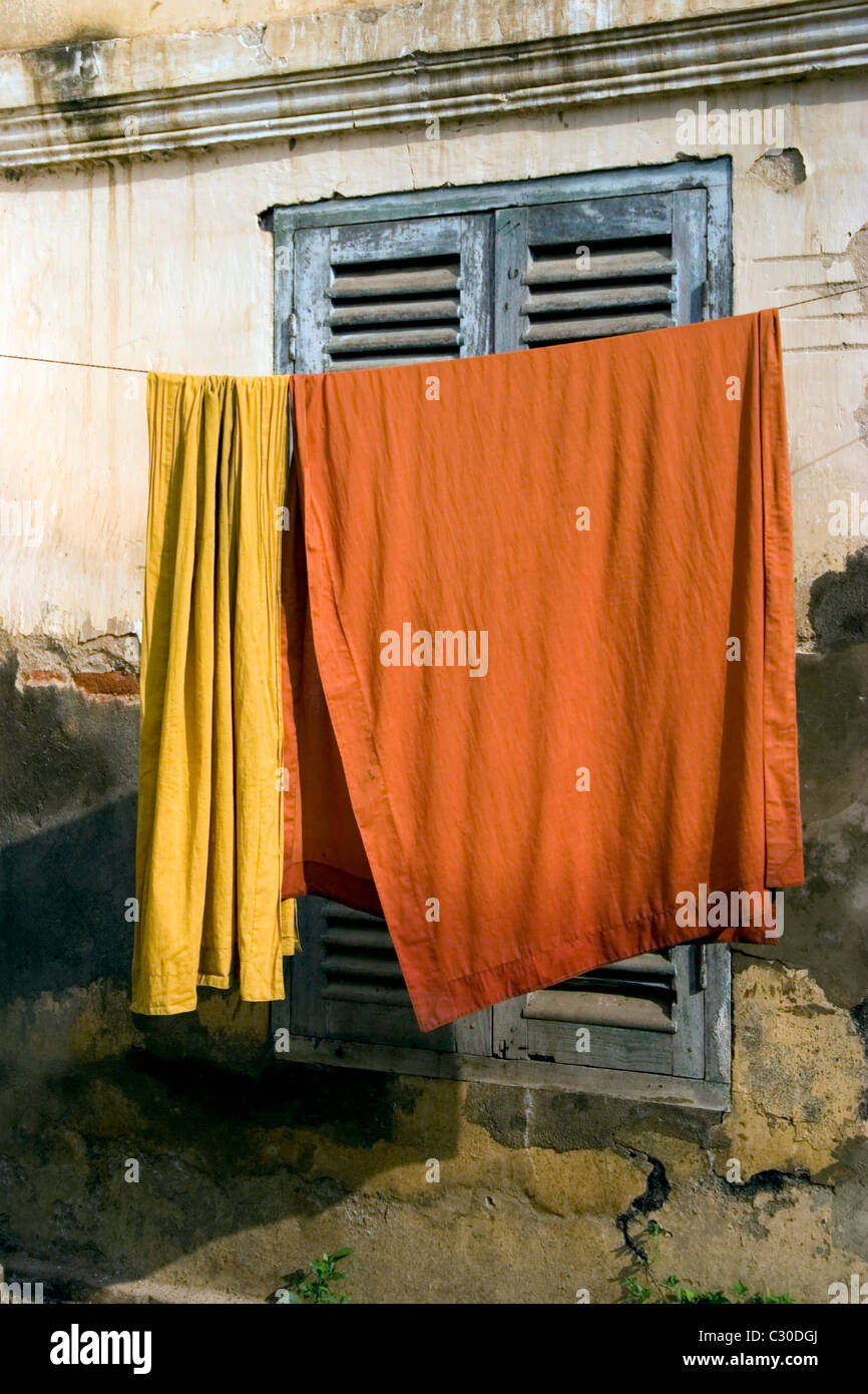 Orange monaco buddista di accappatoi sono appesi su uno stendibiancheria in un tempio fatiscente in Cambogia. Foto Stock