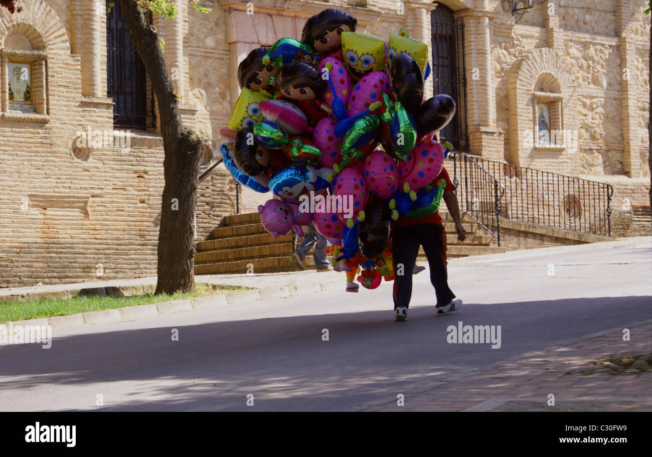 Palloncino elio venditore oltrepassando la chiesa a Alameda Andalusia Spagna Foto Stock