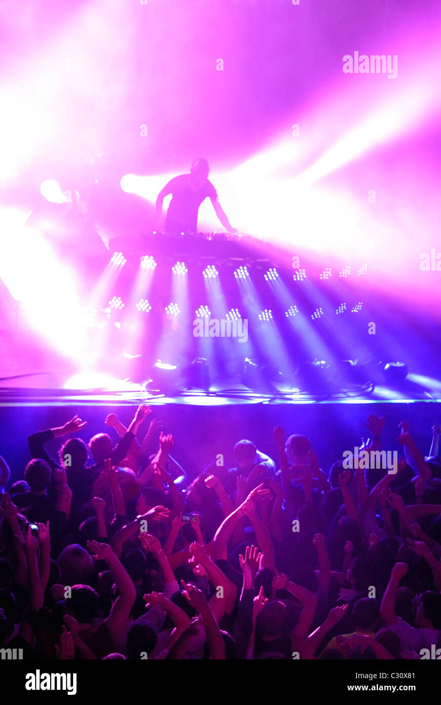 DJ con spettacolo di luci e la folla ad un concerto, club o rave Foto Stock