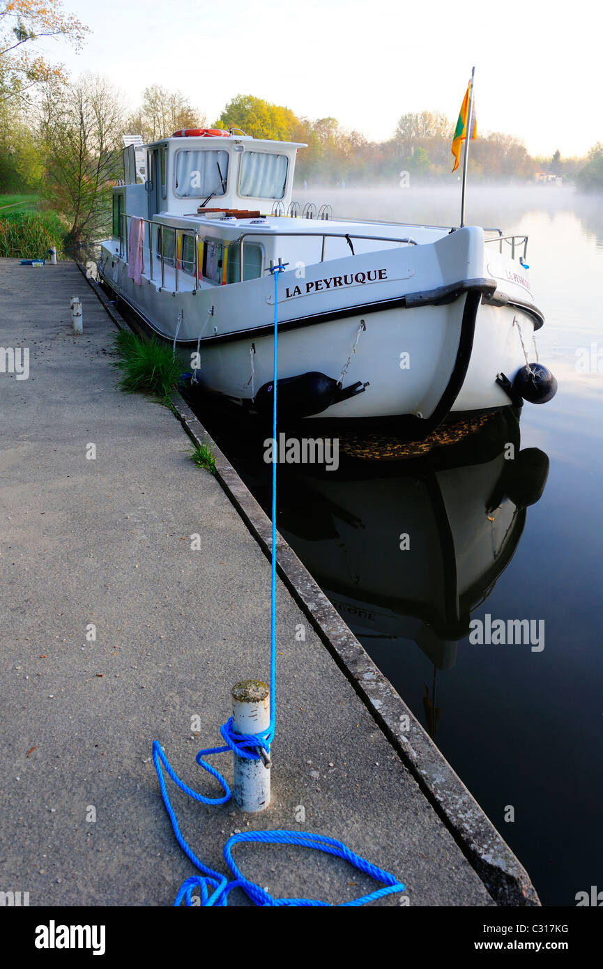 Canal chiatta ormeggiata al mattino presto sul fiume Yonne, Francia, a Charmoy. Spazio per il testo nel cielo. Foto Stock