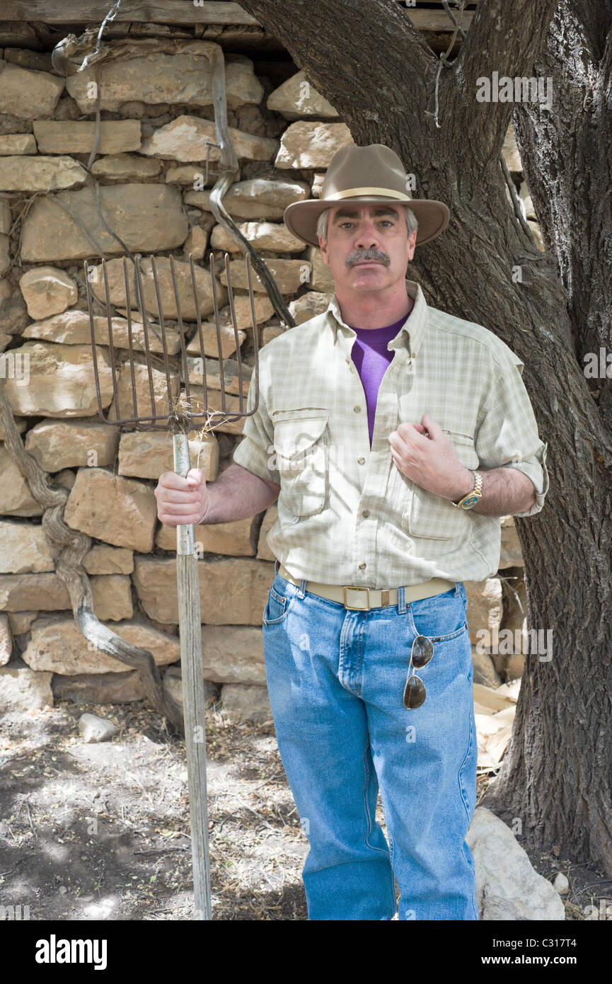 Uomo americano detiene il forcone, che simboleggiano il lavoro agrario, in Hondo Valle, Nuovo Messico. Foto Stock