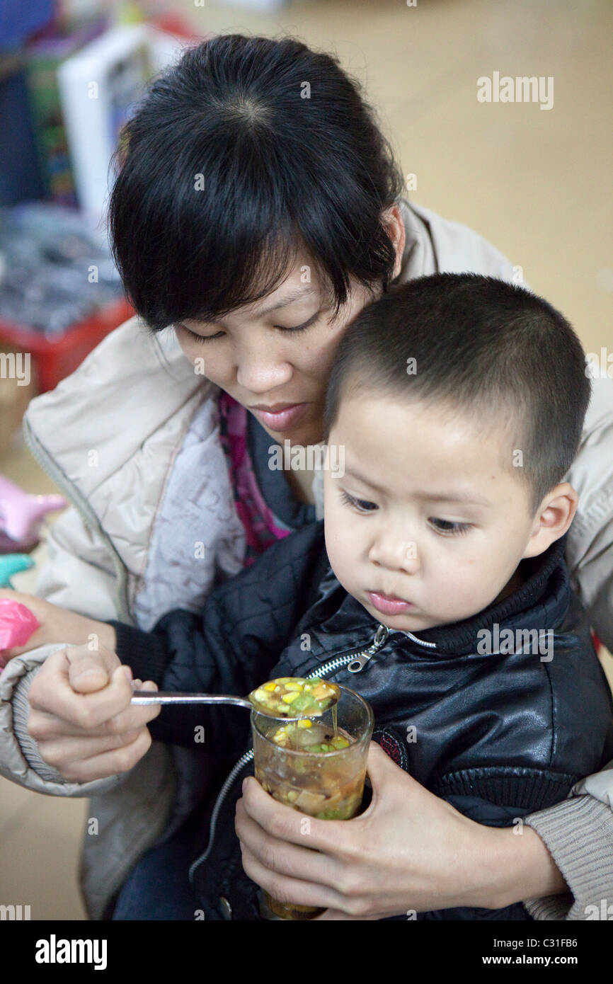 La madre del bambino di alimentazione, Hanoi. Il Vietnam Foto Stock