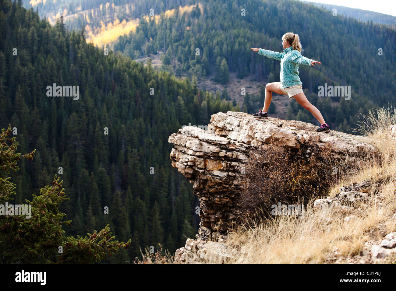 Una giovane donna non lo yoga su una roccia affiorante in Colorado. Foto Stock
