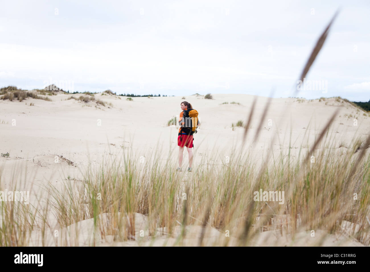 Una ragazza cammina da solo sulle dune di sabbia che indossa uno zaino. Foto Stock