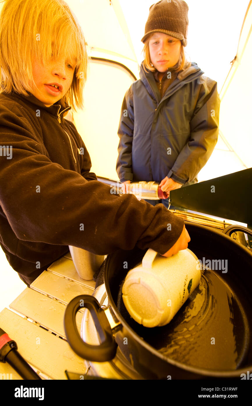 Due fratelli far sciogliere la neve per acqua in California backcountry. Foto Stock