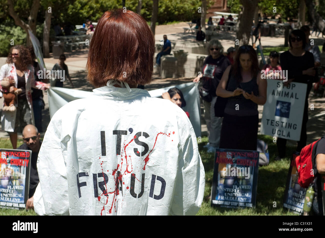Un animale diritti protester indossa una tuta hazmat con sangue finto e le parole "frode" sul retro del si trova di fronte ad una folla. Foto Stock