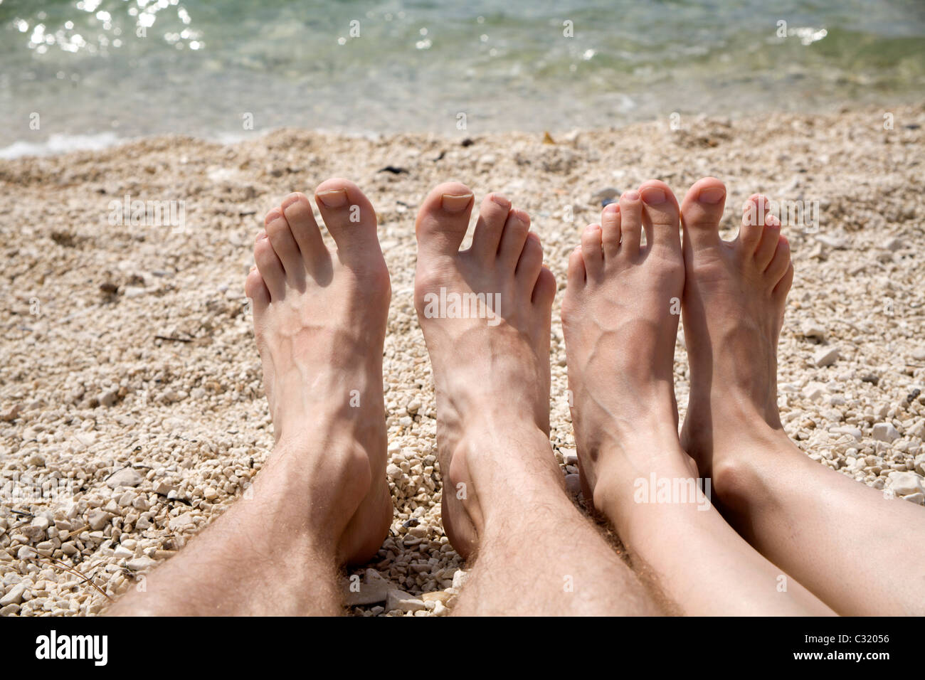 I piedi di un uomo e di una donna in riva al mare - vacanze Foto Stock