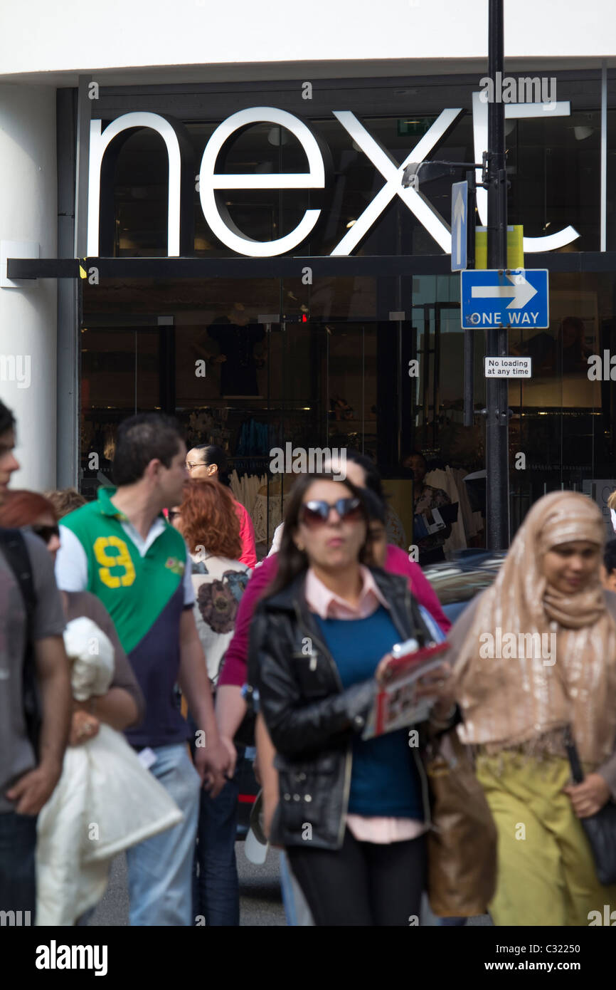 Gli amanti dello shopping passano davanti al negozio Next in una vivace Oxford Street a Londra, Regno Unito. Foto Stock
