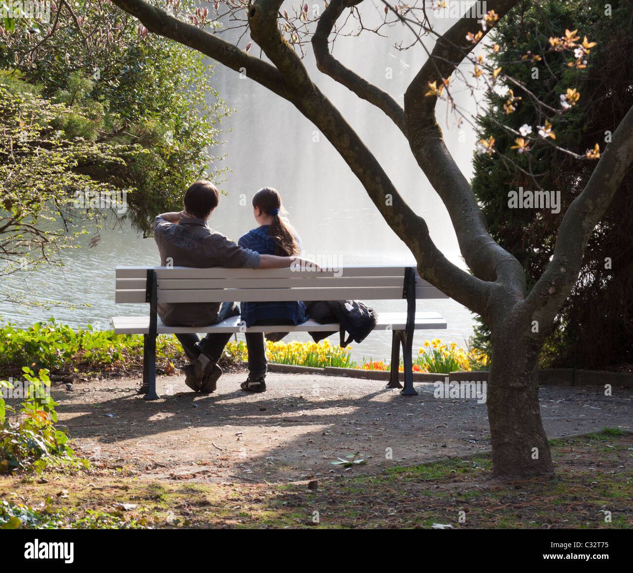 Una giovane coppia in relax il Kurpark di Wiesbaden, la visione di una fontana gioco nel lago. Foto Stock