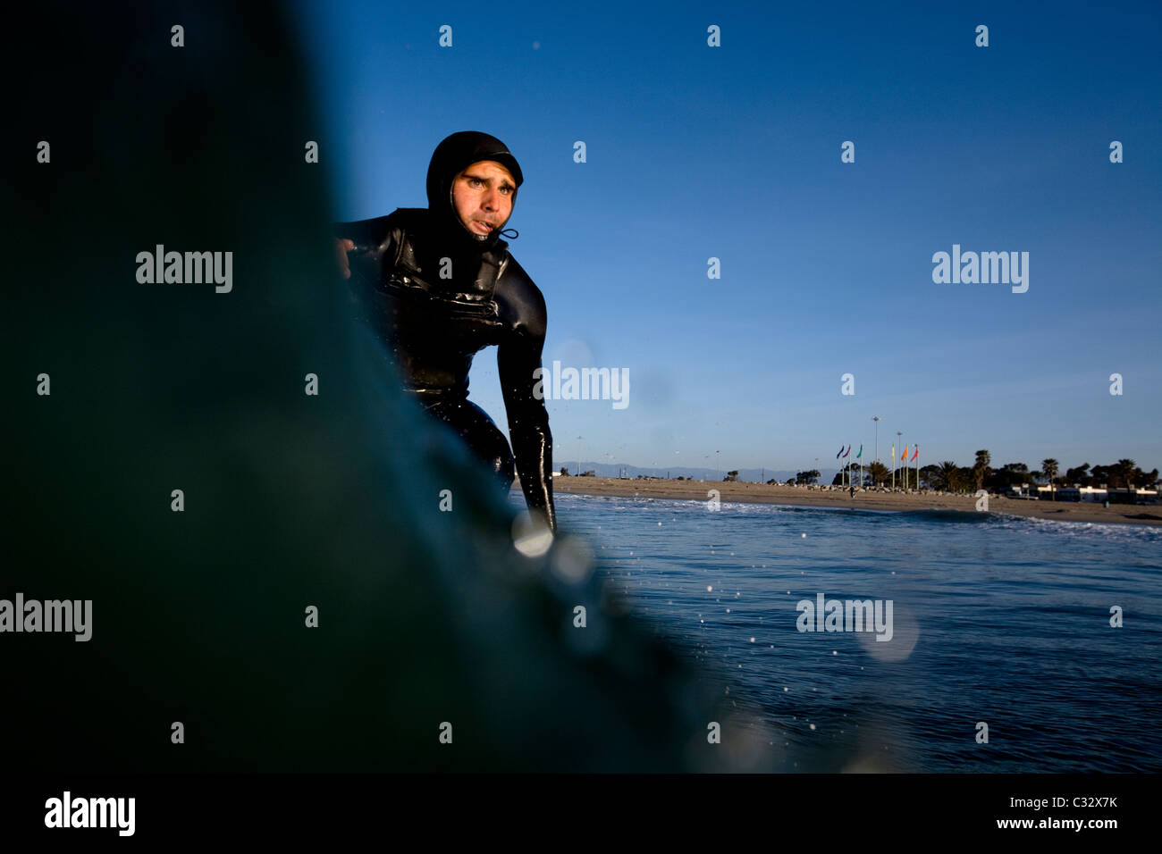 Un surfista che indossa una cappa pompe in giù la linea in Port Hueneme, California. Foto Stock