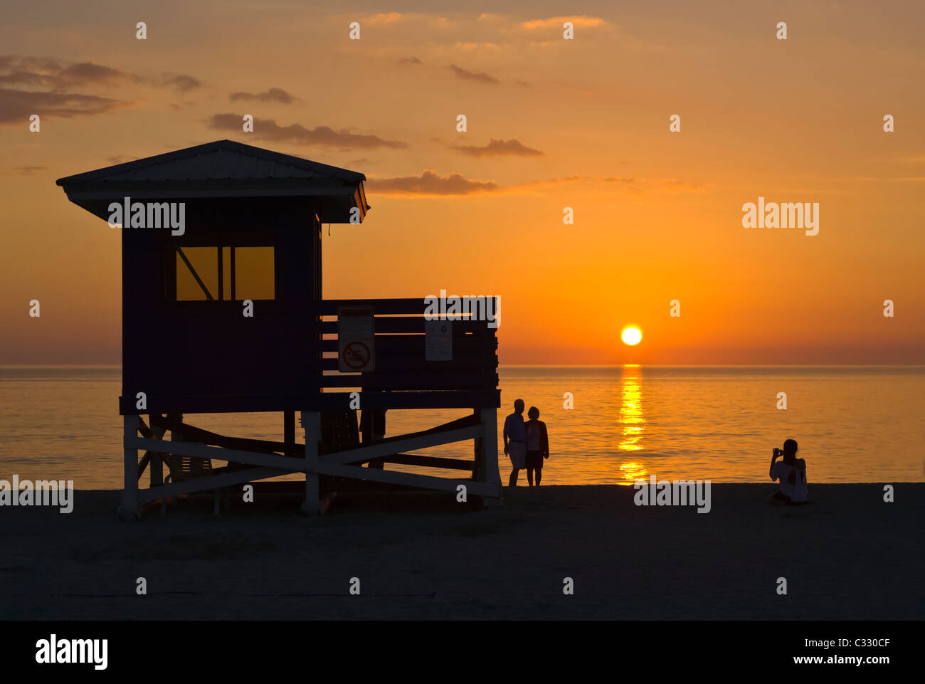 Life Guard stand e persone stagliano aganist arancione tramonto cielo sopra il Golfo del Messico dal Venice Beach Florida Foto Stock