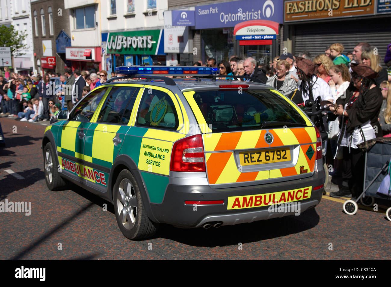 Irlanda del nord servizio ambulanza risposta veloce paramedico il veicolo si sposta attraverso la folla in Regno Unito di sfocatura di velocità Foto Stock