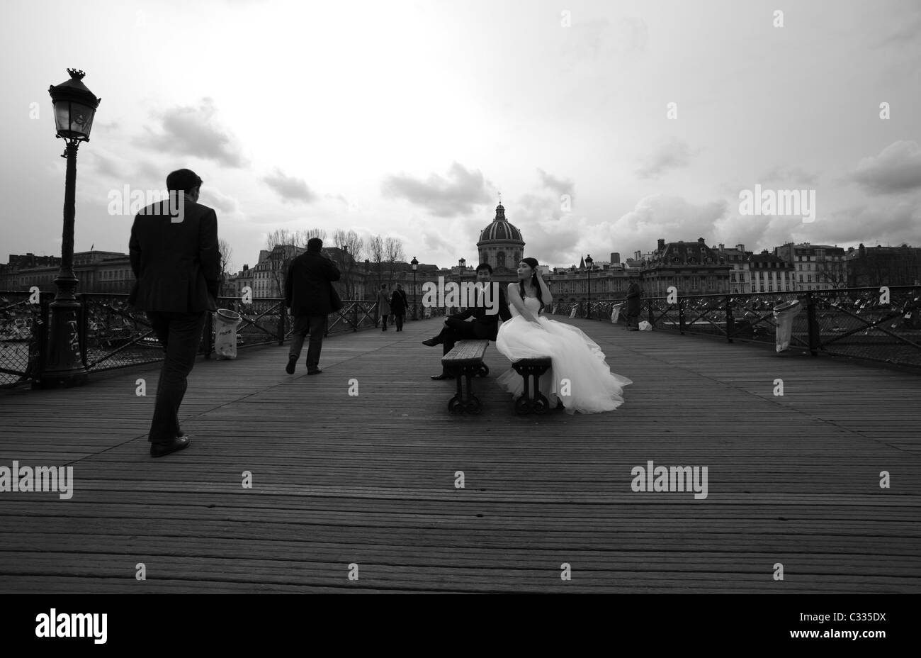 Lo sposo e la sposa seduti su uno dei D'Amour ponti panche guardando gli uni con gli altri mentre i pedoni sono passando da Foto Stock