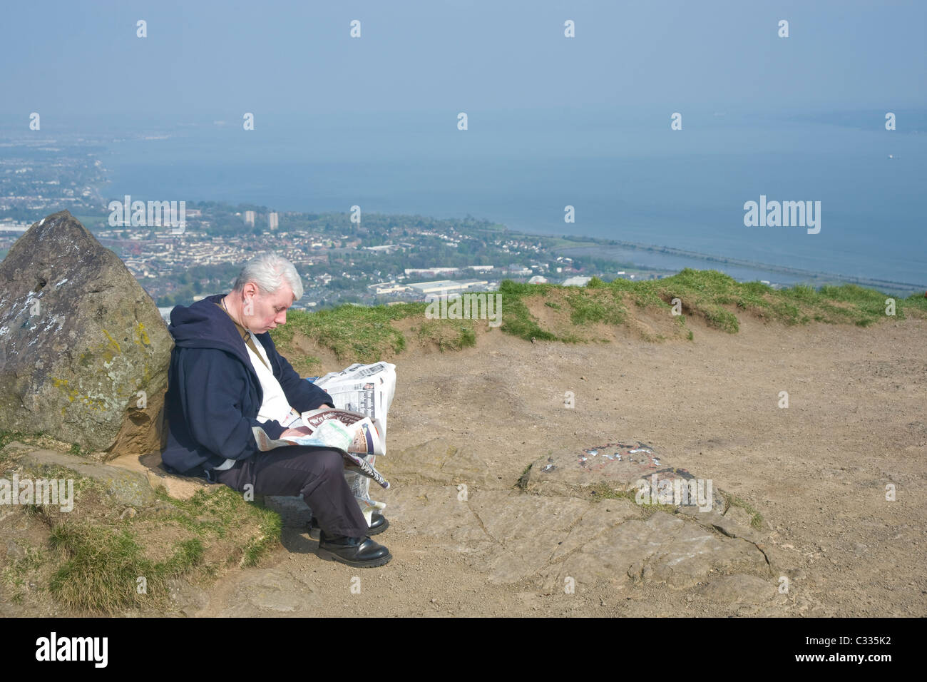 Uomo di lettura carte domenica sulla cima della collina di grotta di Belfast. Foto Stock