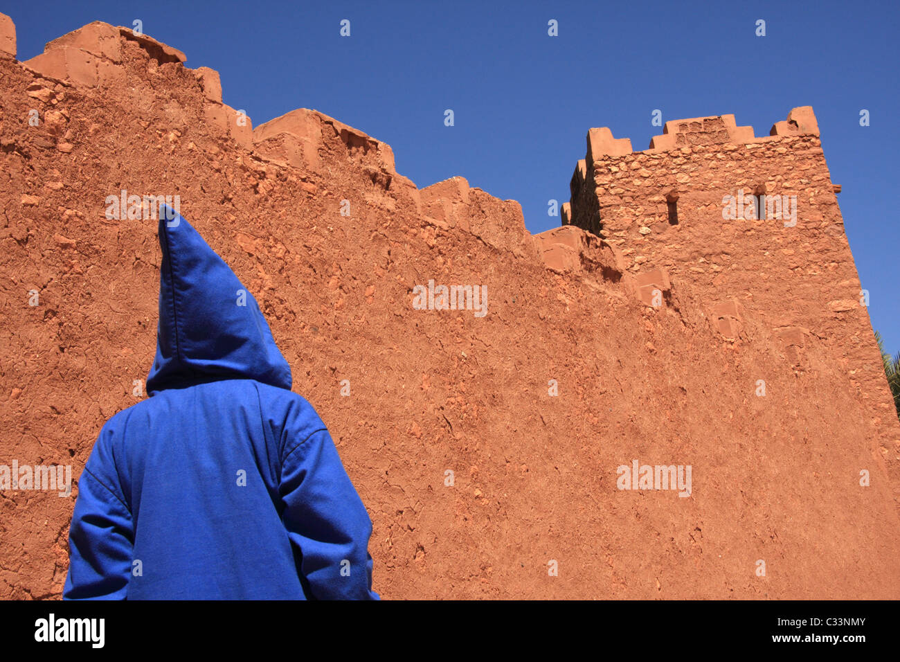 Persona che indossa Marocchino tradizionale jellabah pause di Ait Benhaddou villaggio fortificato, Atlas, regione del sud del Marocco, Africa Foto Stock