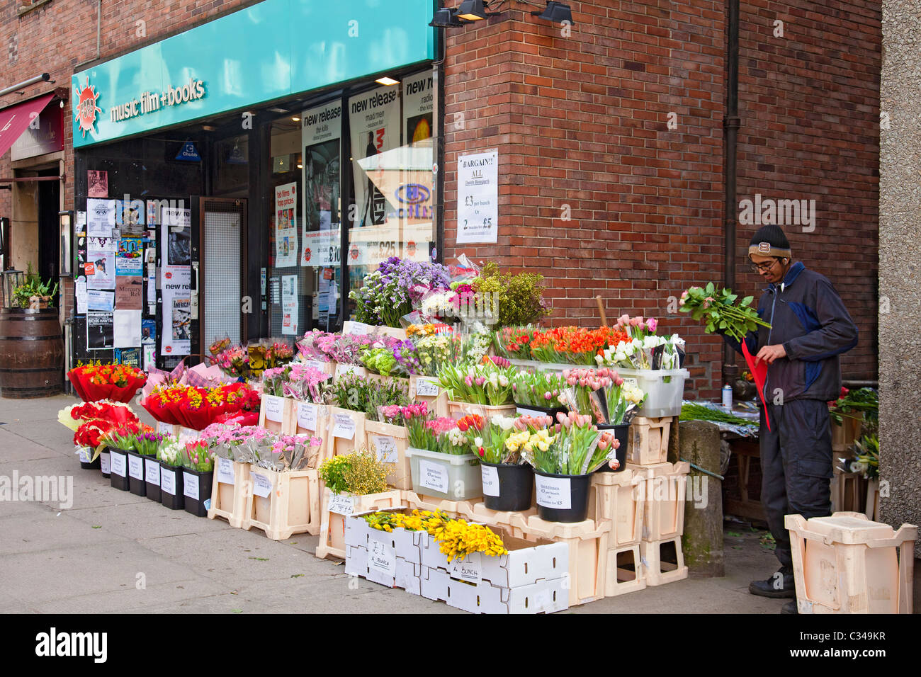 Venditore a vendere fiori in Byres Road, Glasgow, accanto al record FOPP shop Foto Stock