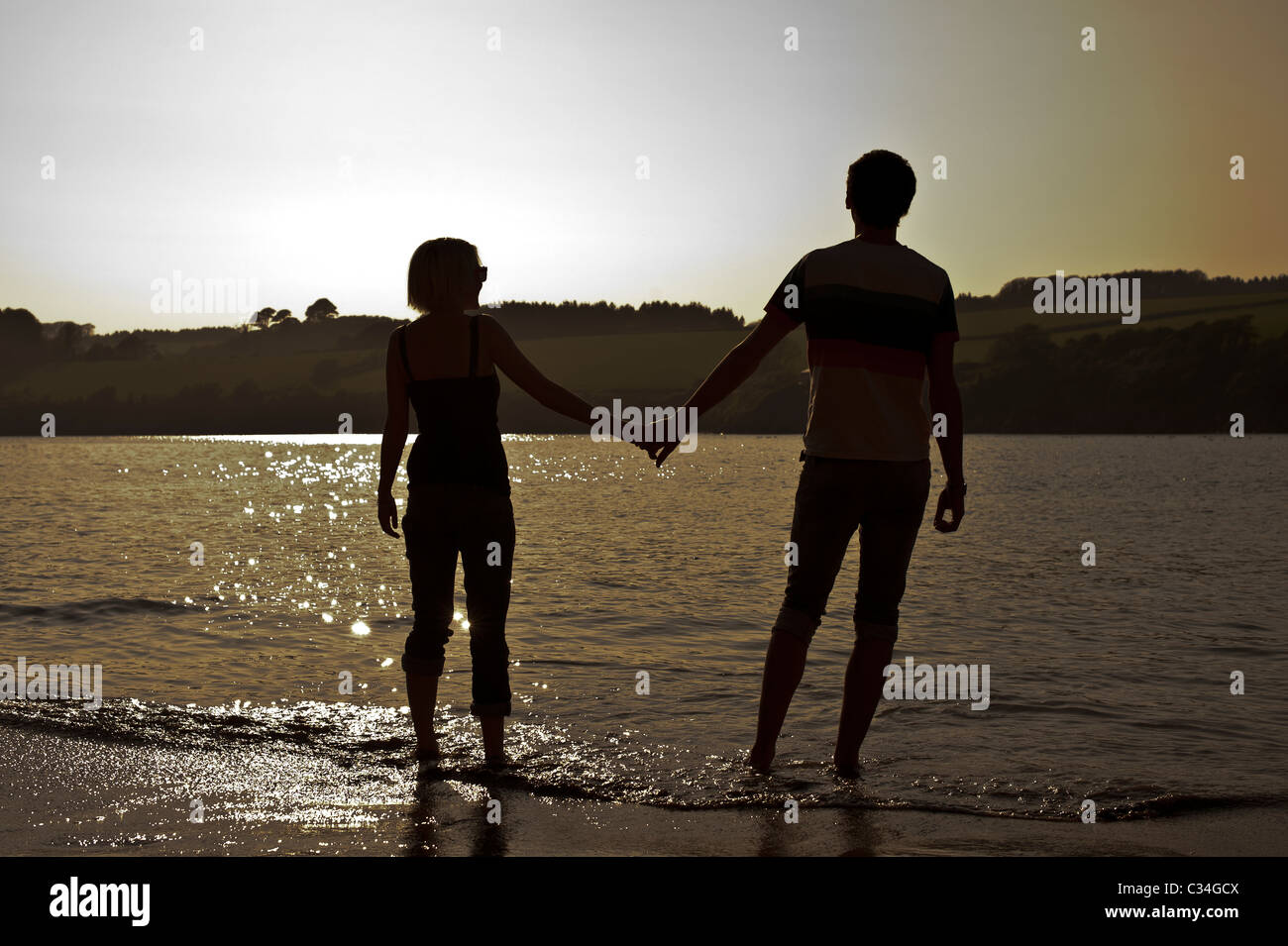 Silhouette di giovane tenendo le mani sulla spiaggia Foto Stock