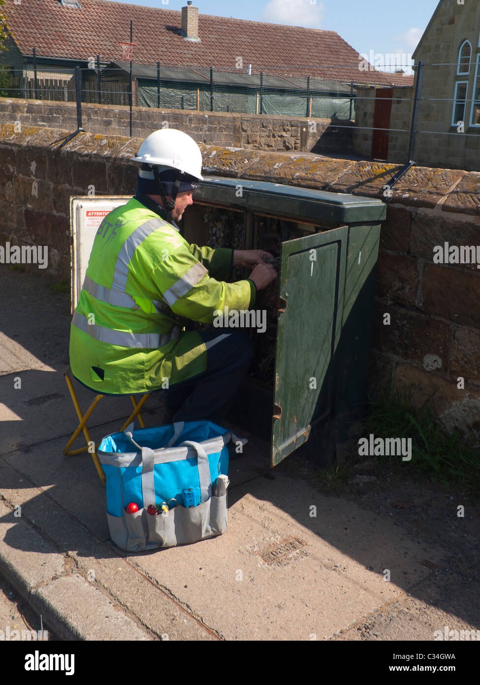 Telecomunicazioni tecnico che lavora su una connessione a banda larga in un armadio stradale nelle zone rurali del Nord Yorkshire Foto Stock