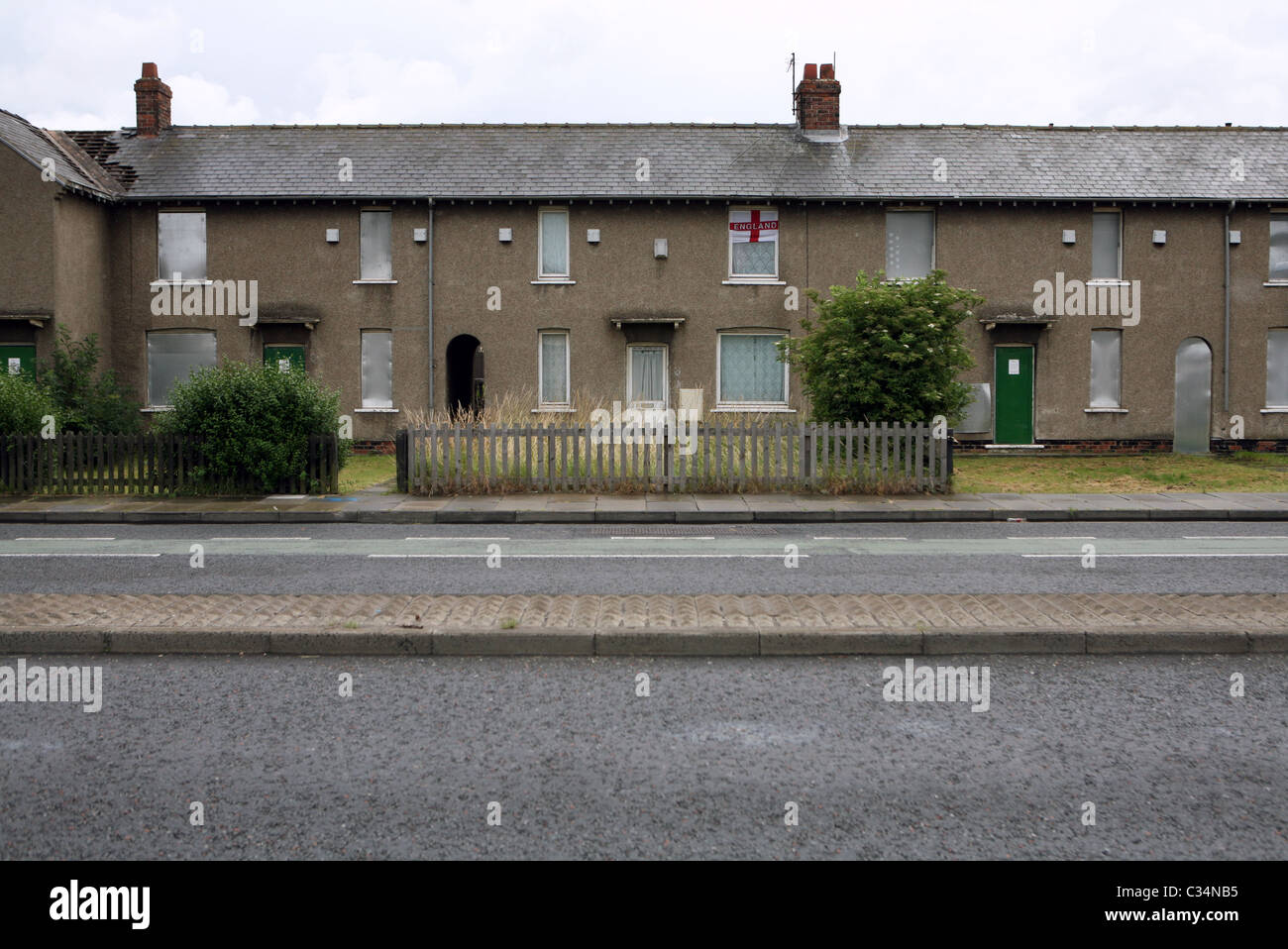 Una casa occupata visualizzando la bandiera di San Giorgio tra intavolato case abbandonate, Grangetown, Middlesbrough, Inghilterra, Regno Unito. Foto Stock