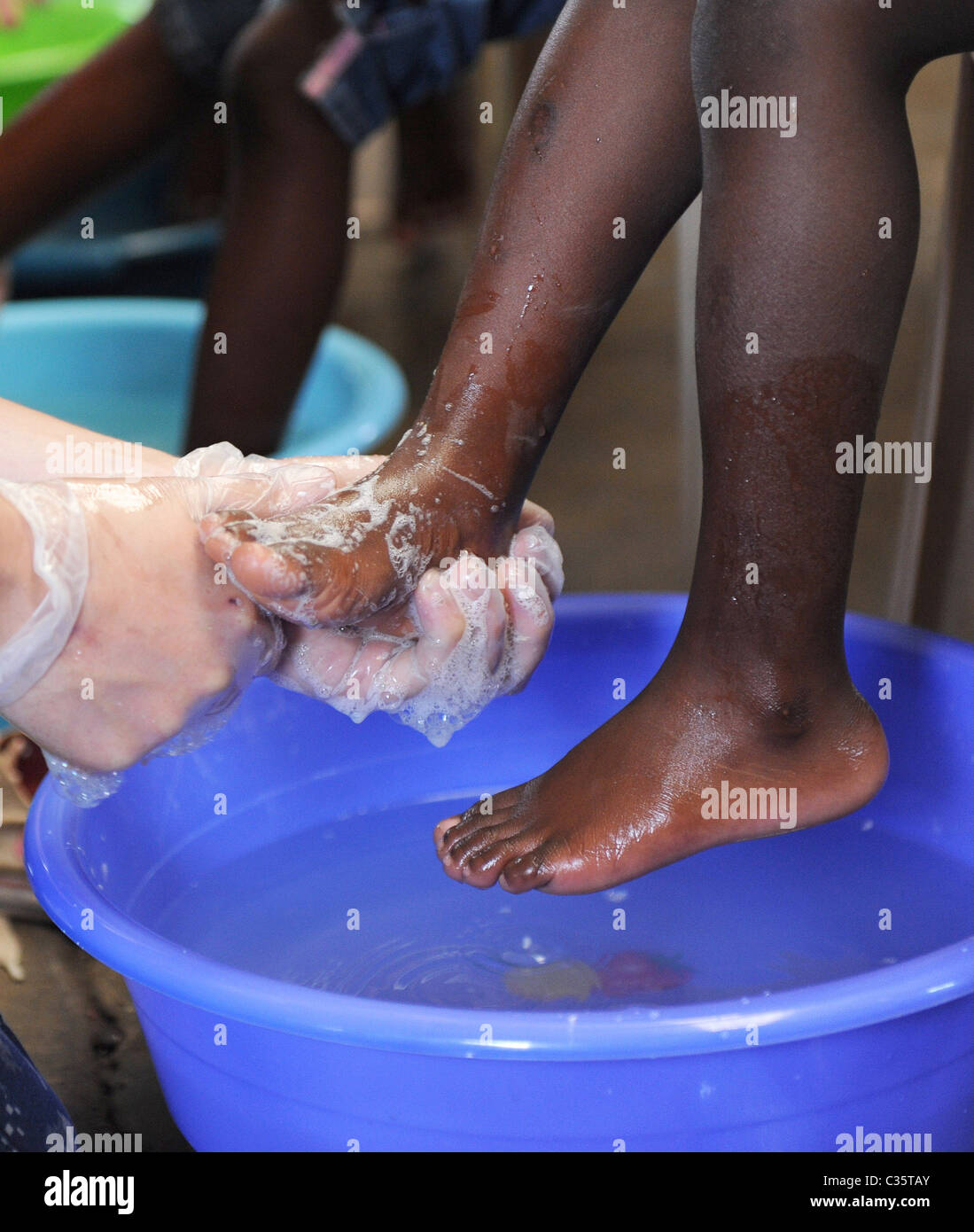 KINGSTON, Jamaica un marinaio bagna un bambino i piedi prima di dare a lui un nuovo paio di scarpe durante la promessa continua scarpa give-away Foto Stock
