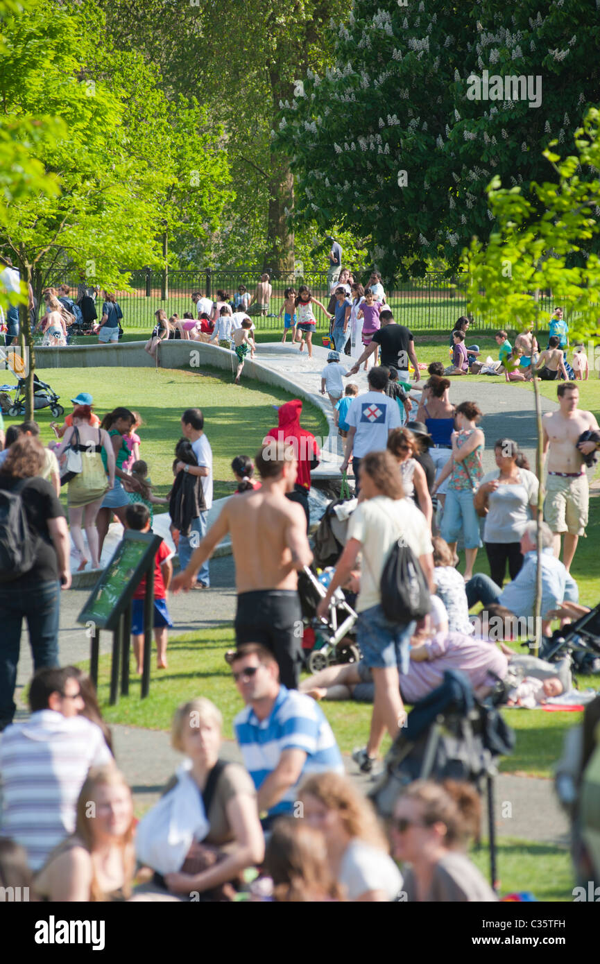 Persone che si rilassano vicino alla Princess of Wales Memorial Fountain a Kensington Gardens / Hyde Park, Londra, Inghilterra, Regno Unito. Foto Stock