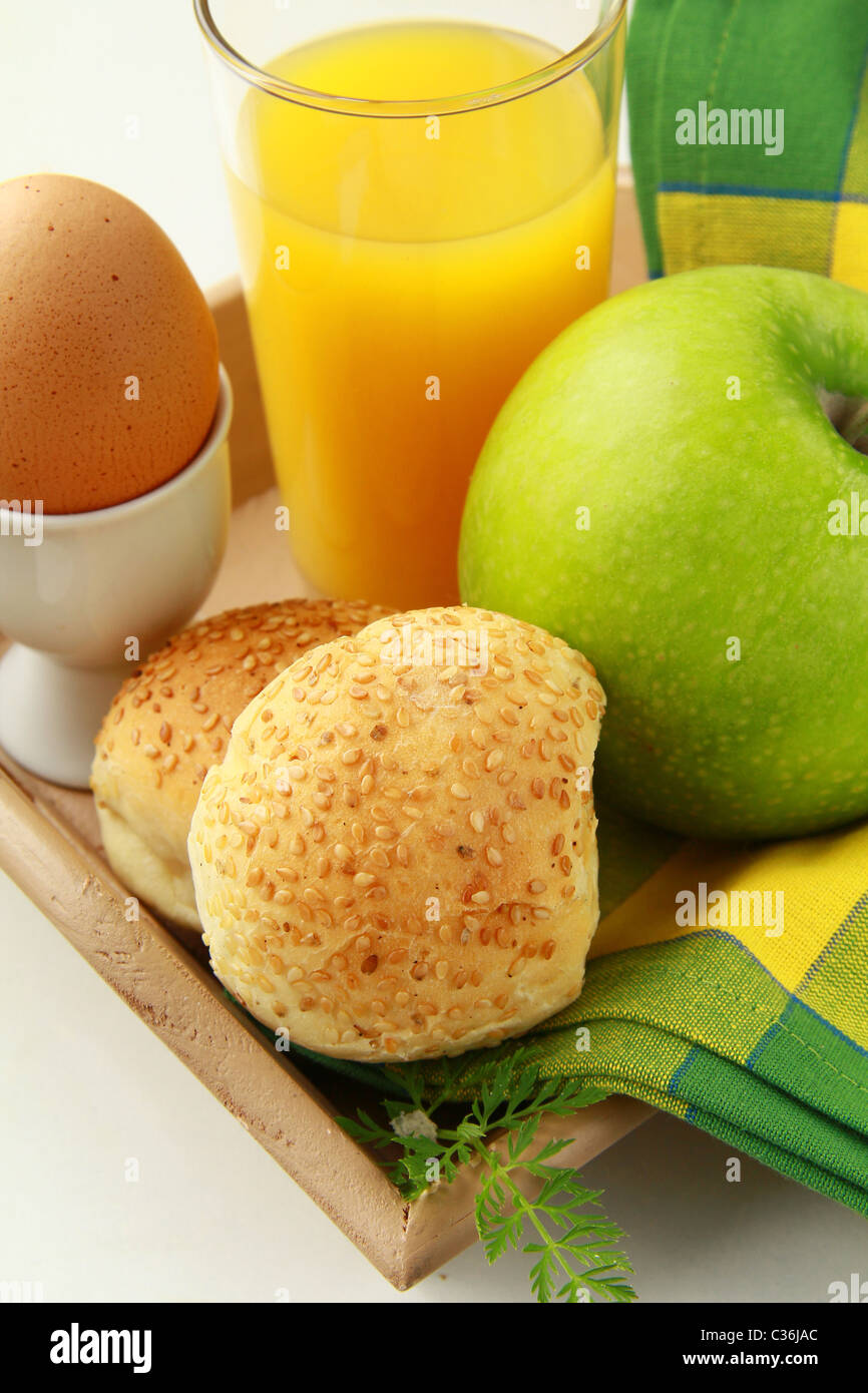 La prima colazione con succo d'arancia, uova sode e ciambelle di sesamo e mela verde Foto Stock