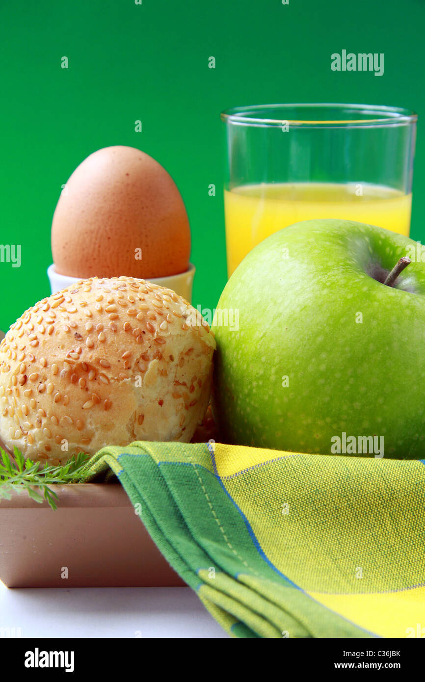 La prima colazione con succo d'arancia, uova sode e ciambelle di sesamo e mela verde Foto Stock