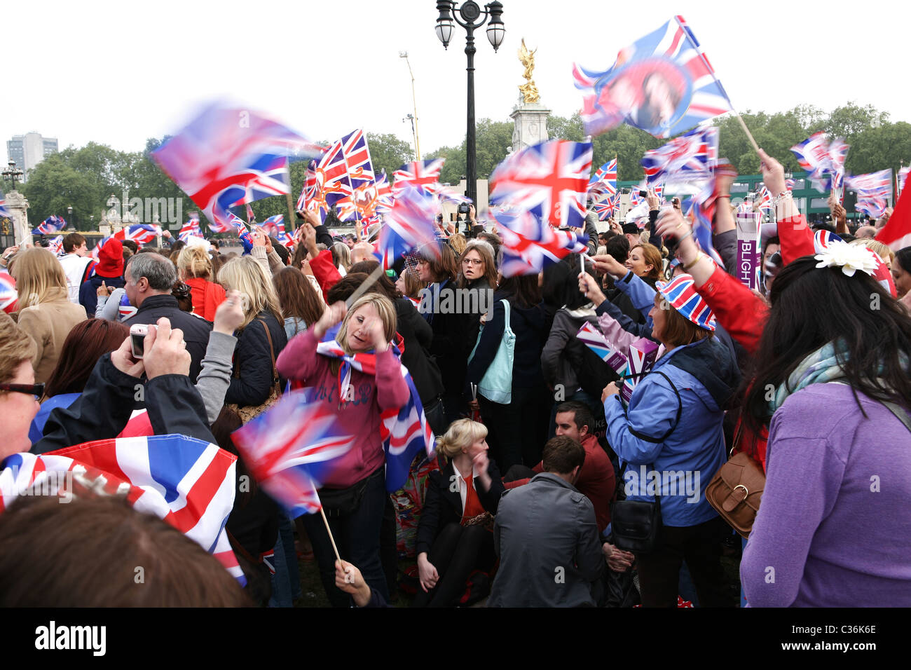 Bandiera sventola dalla folla in attesa per il Royal Wedding tra il principe William e Kate Middleton a Buckingham Palace Foto Stock
